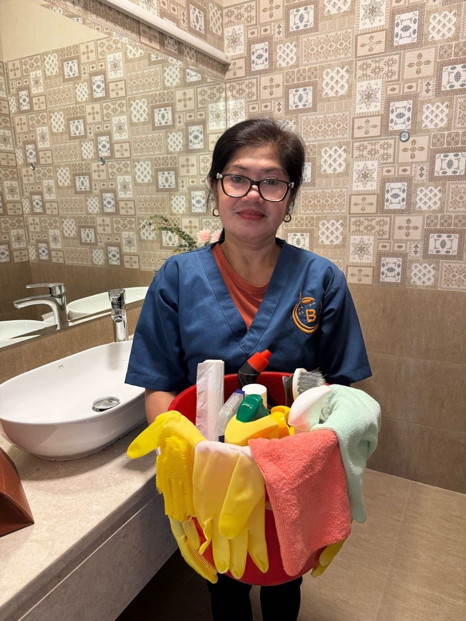 Female cleaner holding a bucket filled with cleaning supplies